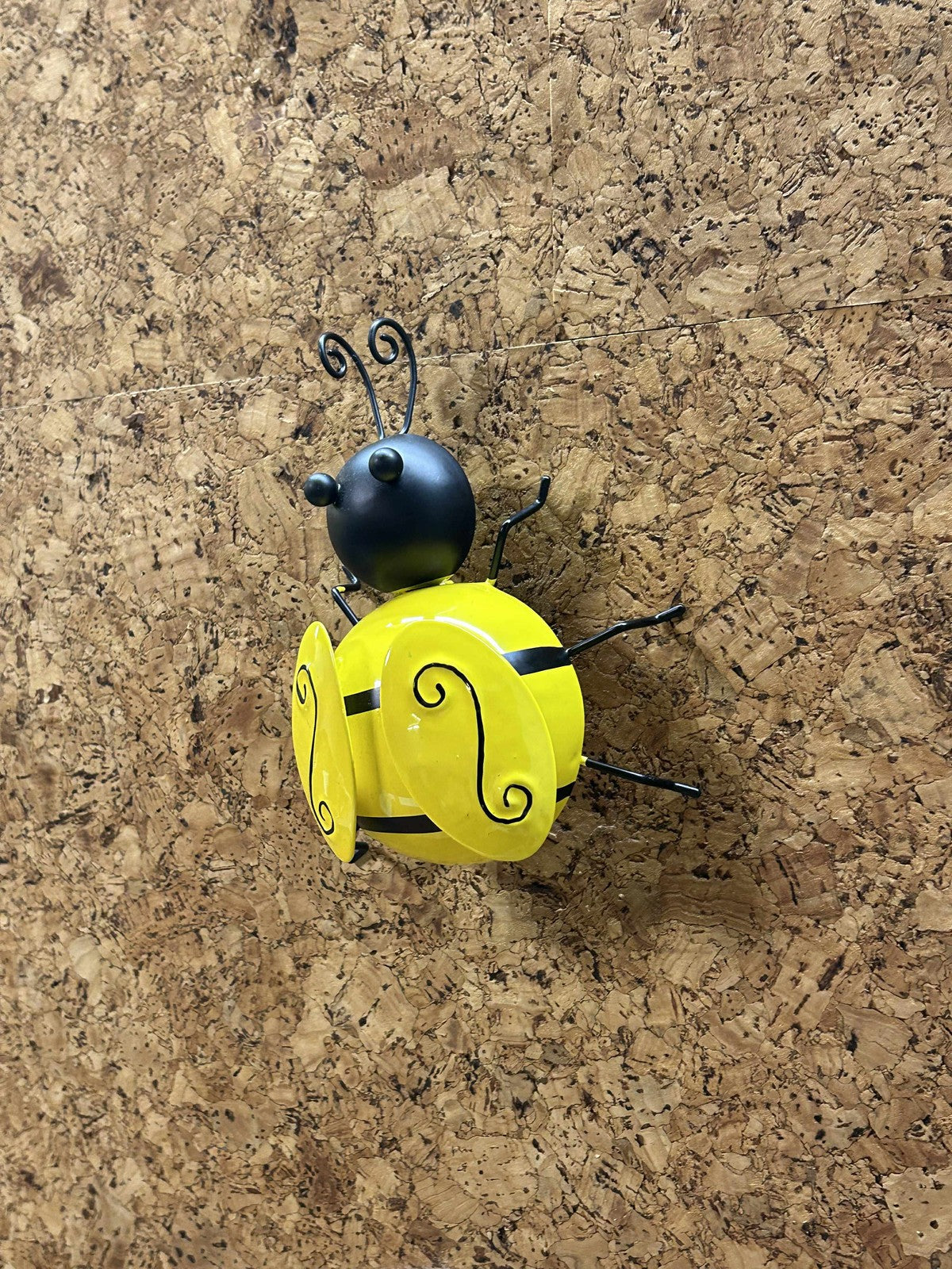 Gul bi i metal, set fra bagsiden. Fremhæver de dekorative vinger og den kunstneriske form.