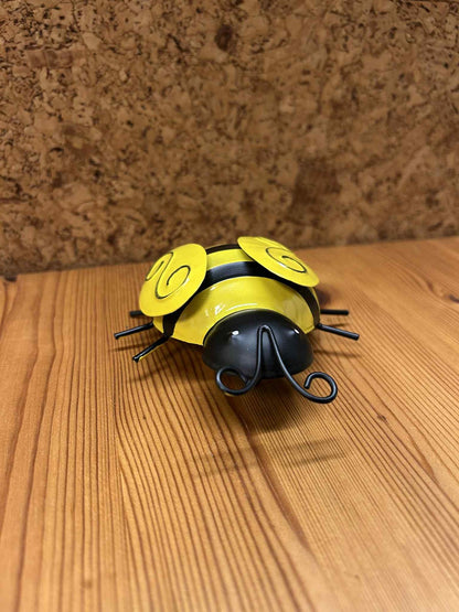 Dekorativ gul mariehøne i metal, set forfra. Fremhæver det unikke kunsthåndværk og den glatte gule overflade. Ideel til gave eller samlerobjekt